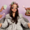 Relaxed young Korean woman in soft bathrobe, wears cosmetic patches under eyes, prepares for evening party, surrounded with many hands holding beauty items. Health care and wellbeing concept